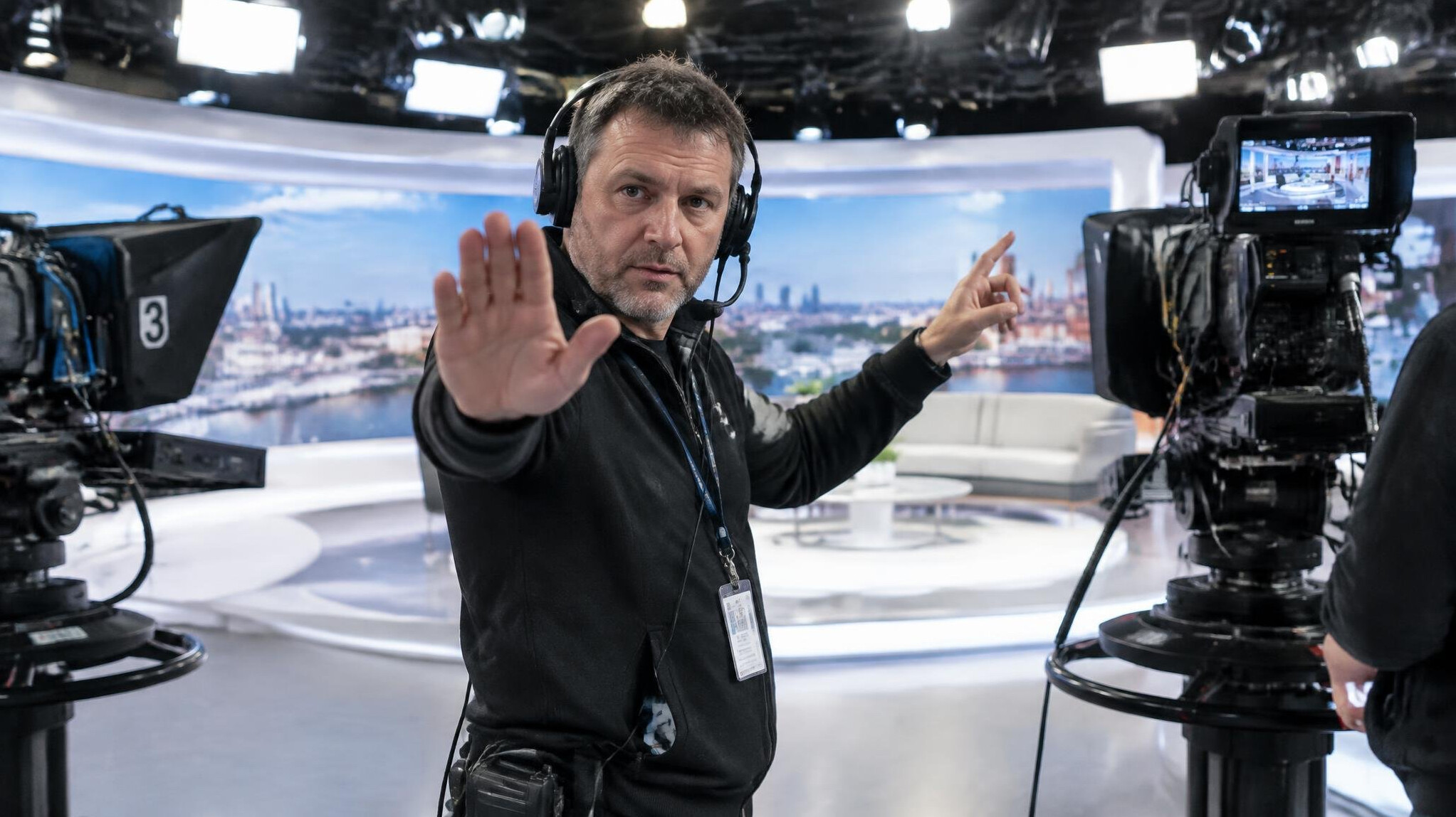 Floor manager giving hand signals on a TV studio set